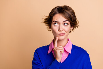 Photo portrait of pretty young girl look skeptical unsure empty space dressed stylish blue outfit isolated on beige color background