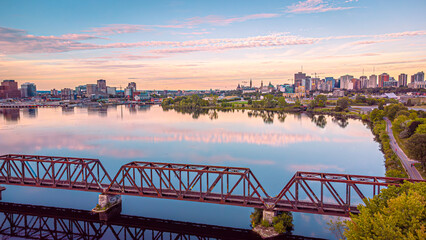 Aerial panorama view of downtown Ottawa and Gatineau, Chief William Commanda Bridge, national capital region, golden hour sky reflecting on the Ottawa River, Ontario, Quebec, Canada (September 2021)
