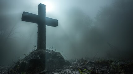   A cross atop a hill, shrouded in foggy forest, sun piercing through mist