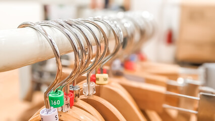 Close-up view and selective focus of empty wooden hangers with colorful plastic size tags indexes...