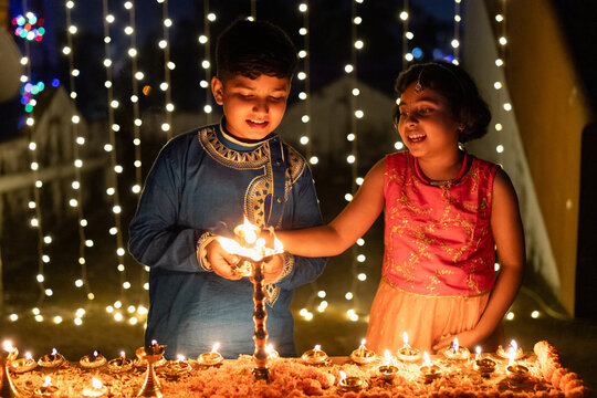 Brother and sister lighting oil lamps during diwali