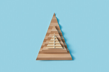 Christmas trees from cardboard stacked on blue studio background