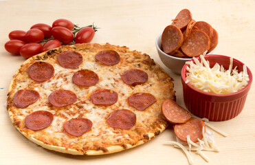 a pepperoni pizza on a wooden board surrounded by pepperoni cheese and tomatoes
