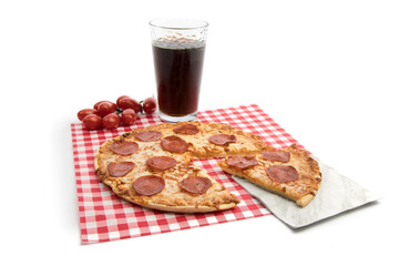 a slice cut out of a pepperoni pizza with a glass of cola on a red checked background isolated on...