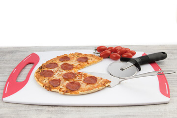 a pepperoni pizza on a white cutting board with a pizza cutter on a grey table