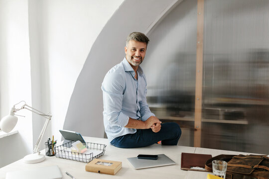 Portrait of happy man sitting at office desk looking at camera