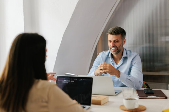 Happy businessman discussing in the office with his female colle