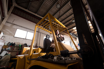 Confident female industrial worker on forklift
