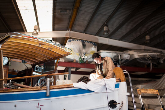 Focused woman working restorating boat at workshop
