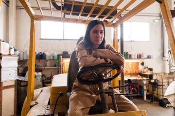 Smiling female mechanic sitting on forklift machine