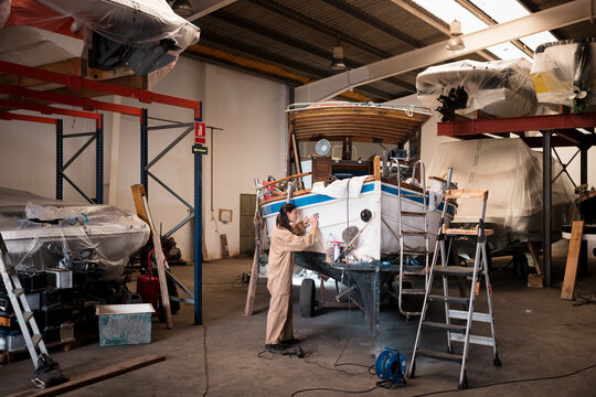Focused female technician working on boat restoration