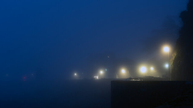 Dark foggy night with glowing street lights 