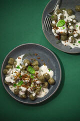 Integral gnocchi with wild herbs and ricotta sauce on a green dark background. Proper nutrition, traditional recipes of Northern Italy in a new interpretation