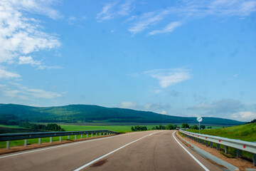 A road leading into the distance. Road against the background of a blue sky with clouds. beautiful landscapes with mountains