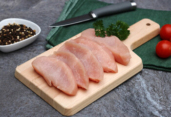 Fresh turkey cutlets on a kitchen board.