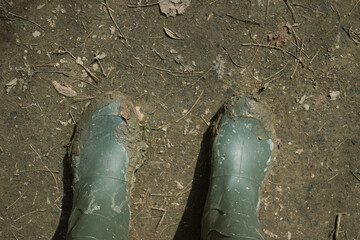 Rubber boots dirty with mud. Concept of adventure and tourism.