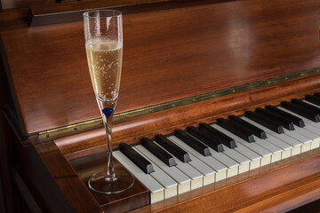 a traditional glass flute of bubbly champaign on a piano keyboard