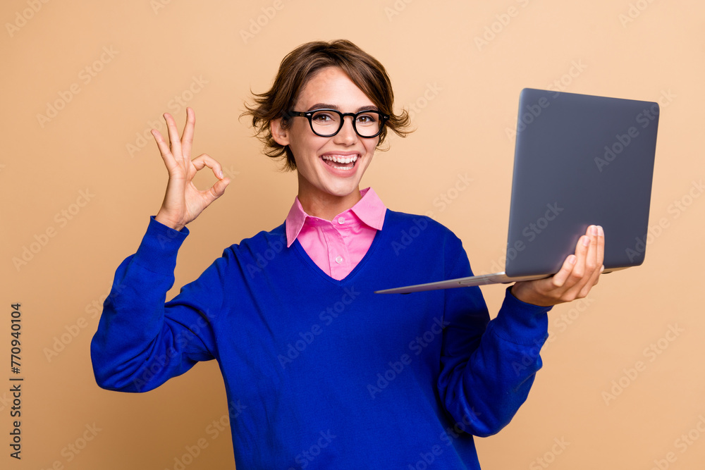 Wall mural Portrait of charming positive recruiter lady hold wireless laptop demonstrate okey symbol isolated on beige color background