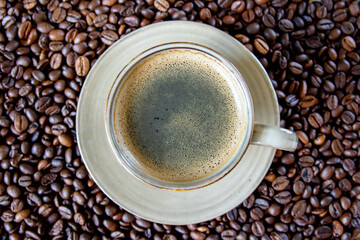 Cup with coffe on the roasted coffe beans.