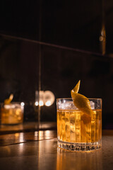 Yellow alcoholic cocktail with ice and lemon zest on a background of a concrete surface