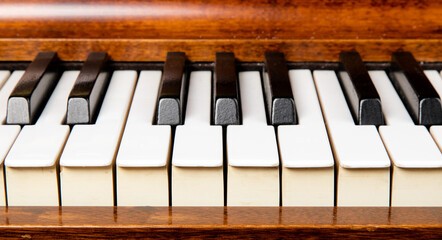 a full  octave of black and white keys from middle c on an an old rosewood piano keyboard