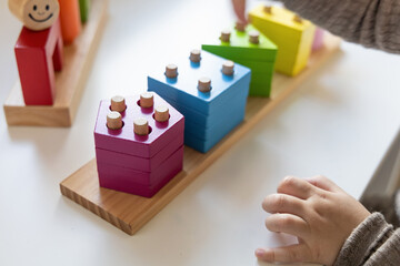 Child playing a fun-filled game of logic with colourful wooden blocks. Game of logic. Educational games for children and earlier development. 