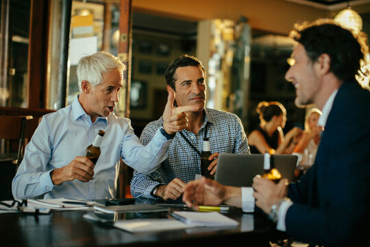 Businessmen drinking beer after work at bar