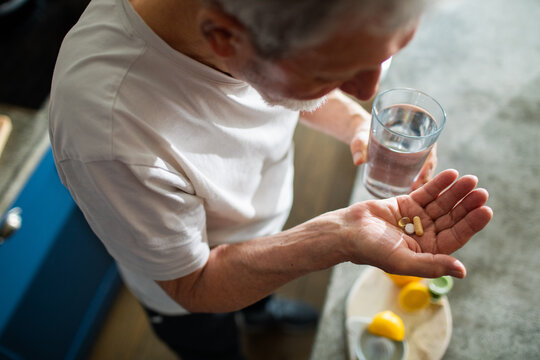 Senior man holding supplements and glass of water