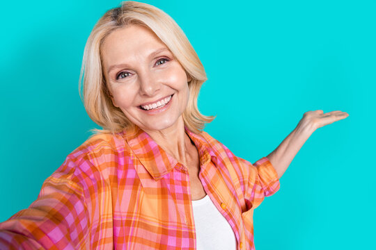 Photo of good mood woman straight hair dressed checkered shirt making selfie demonstrate empty space isolated on teal color background