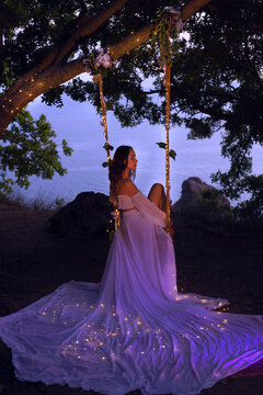 magical photo. girl on a swing in a white dress
