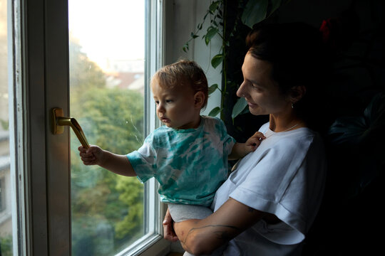 Mother holds her son by the window