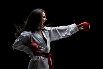 girl exercising karate punch and screaming against black background