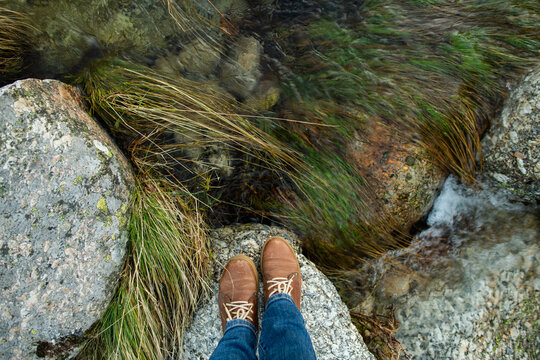 Moutntain river, stones and feet wearing boots
