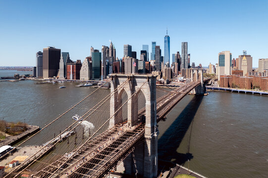 Brooklyn Bridge with city skyline backdrop under blue sky.