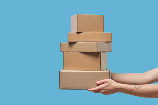 Close up of female hands holding stack of cardboard boxes