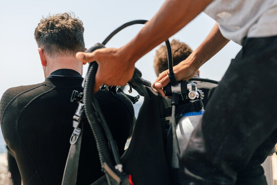 Scuba Diver being assisted to put on BCD
