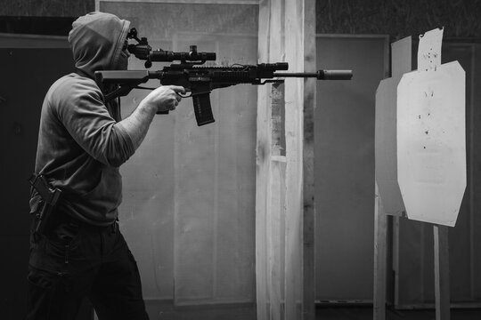 A man trains tactical shooting with a rifle and at a shooting range at a target. Black and white photo.