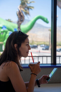 Woman Drinking A Cold Coffee Drink At A Store Bar