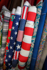Patriotic bolts of fabric are stored together on the shelf at this local fabric store.  Stars, stripes, and stars adorn this canvas material.  Cloth with an American Flag theme for sale.