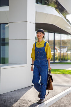 Dedicated woman walking by corporate building outside office