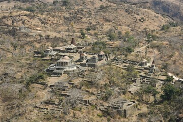 Cluster of ruins and foundation walls of ancient Jain temples in South central sector of Kumbhalgarh Fort complex, India, nestled in barren dry season dusty savannah of Aravalli Hills