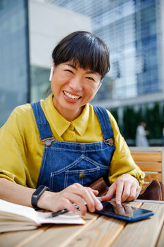 Smiling freelancer taking notes while using smart phone at cafe