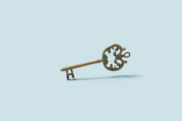 Old bronze key with levitating over light blue studio background