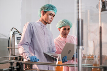 Specialist in factory checking bottles. Two female worker inspecting quality of plastic water tank on conveyor belt in drinking water factory.