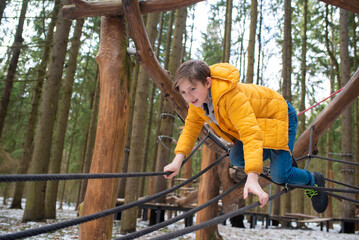 a boy having fun on adventure rope park in winter. Active leisure for kids.