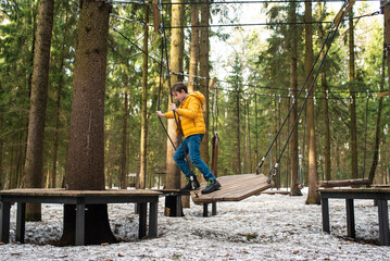 11 year old boy on a rope playground going through an obstacle course in a snow park	