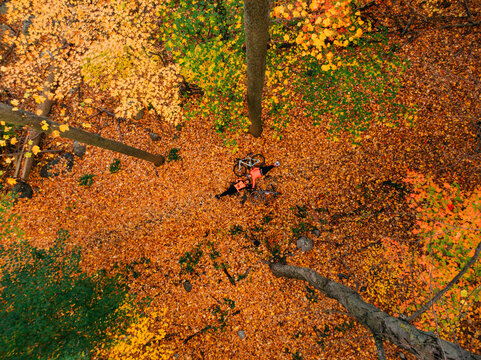 Couple with bicycles posing on the fallen leaves in an autumn forrest