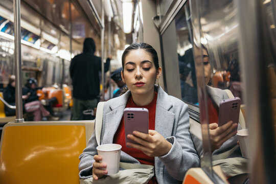 Woman using smartphone commuting on the subway - Powered by Adobe