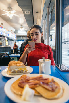 Young woman having breakfast and taking photos