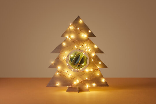 Cardboard Christmas tree decorated with baubles and glowing garlands